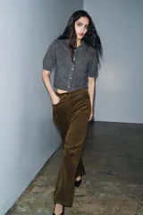 Chaqueta de punto con textura cepillada, cuello polo y manga corta. Presenta cierre frontal con botones y diseño de corte recto.