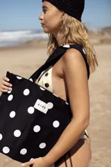 Tote bag de algodón color negro con estampado de lunares blancos. Cuenta con doble asa de hombro y etiqueta frontal con el logo de la marca.
