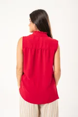 Camisa roja sin mangas con cuello mao adornado con un volado y cierre frontal con botones.