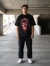 Remera oversize negra con estampado gráfico en rojo y blanco de Michael Jordan sonriendo, usando una gorra de béisbol con la palabra "CHAMPIONS" y gafas de sol. Incluye una firma estilizada en rojo en la parte inferior del gráfico.