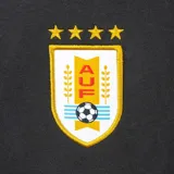 Pantalón de entrenamiento negro para mujer, de corte jogger con puños ajustados y cordón en la cintura. Presenta el escudo de la Asociación Uruguaya de Fútbol (AUF) con cuatro estrellas bordado en amarillo y blanco en la pierna izquierda, y el logo de Nike en blanco en la pierna derecha.