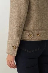 Campera de lana fina sin teñir, con cuello alto, cierre frontal completo y diseño de corte recto con pespuntes decorativos en puños, ruedo y cuello.