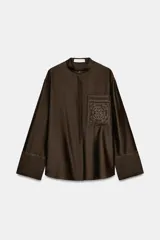 Camisa ZW Collection de color marrón oscuro, con cuello mao, manga larga con puños anchos y cierre frontal oculto por solapa. Cuenta con un bolsillo de parche en el pecho adornado con bordados a tono, los cuales también se repiten en los puños.
