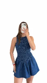 Vestido corto de denim liviano, sin mangas y con cuello redondo. Presenta un cuerpo fruncido y elastizado que se ajusta a la silueta, y una falda corta de corte evasé con vuelo.