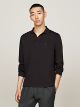 Chomba de manga larga Tommy Hilfiger color negro, confeccionada en algodón. Presenta cuello tipo polo, tapeta de dos botones y logo bordado en el pecho.