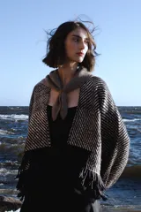 Chaqueta abierta de lana con diseño de rayas diagonales en tonos taupe y negro, con terminación de flecos en el ruedo y mangas amplias.