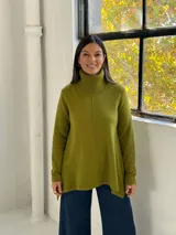 Sweater de punto color verde pistacho, con cuello alto tipo polera, mangas largas y diseño holgado con costuras verticales decorativas.