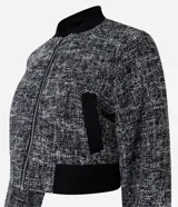 Campera bomber corta confeccionada en tweed con cuello alto, cierre frontal con cremallera, bolsillos y detalles en rib.
