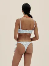 Conjunto de bikini con estampado de cebra en tonos celeste y blanco. El corpiño es de corte recto con tirantes finos y la bombacha es tipo colaless con tiras ajustables en los laterales.