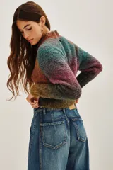 Cardigan de punto con diseño multicolor en tonos tierra y violeta, de corte cropped y manga larga. Presenta cierre frontal con botones oscuros y cuello redondo.