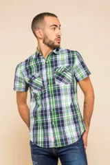 Camisa de manga corta con estampado de cuadros en tonos verdes, azules y blancos. Presenta cuello clásico, cierre frontal con botones y dos bolsillos delanteros con solapa.
