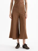 Pantalón de corte culotte en color marrón, confeccionado en tejido de punto con piernas amplias. Presenta detalles de recortes con pespuntes visibles, cintura con elástico y cierre lateral.