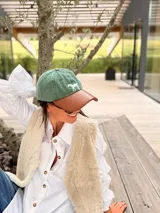 Gorra tipo polo con cuerpo de tela verde y visera de cuero marrón, con un caballo bordado en el frente.