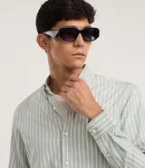 Camisa de corte regular confeccionada en una mezcla de bambú y poliéster, con diseño de rayas verticales en tono verde claro y blanco. Presenta cuello inglés, cierre frontal con botones y mangas largas con puños ajustables.