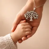 Dije de acero con diseño calado de árbol de la vida, de forma circular.