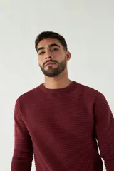 Sweater negro de punto con textura acanalada horizontal, cuello redondo y logo bordado en el pecho.