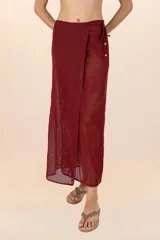 Falda pareo larga color vino, de tejido calado con bordado floral y detalle de cuentas en los pliegues.