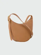 Cartera crossbody tamaño S de Longchamp, modelo Le Foulonné, color tostado. Confeccionada en cuero graneado, de diseño estructurado en forma de media luna, cierre superior con cremallera y herrajes metálicos dorados.