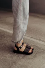 Sandalia de cuero color tostado con tiras anchas, tira en el talón y hebilla metálica rectangular ajustable. Cuenta con suela de goma con tacón bajo y plataforma.