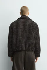 Cazadora de corte boxy fit confeccionada en tejido con textura waffle y acolchado interior. Presenta cuello solapa, cierre frontal con botones a presión, mangas largas con puños elásticos y bolsillos de vivo en la cadera.