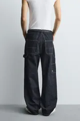 Jeans de hombre relaxed straight fit, color azul oscuro, confeccionados en denim rígido sin prelavados. Presentan cinco bolsillos, bolsillos plastrón y tira multifunción en las perneras. Cierre frontal con cremallera y botón.