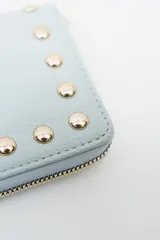 Billetera negra con cierre perimetral y tachas doradas decorativas en el borde frontal.