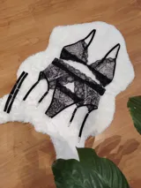 Conjunto de lencería compuesto por bralette triangular y bombacha tipo colaless, confeccionados en microtul estampado con detalles de encaje negro. Incluye portaligas desmontable con tiras ajustables.