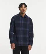 Camisa de manga larga con diseño de cuadros en tonos marrones, confeccionada en algodón. Presenta cuello camisero, cierre frontal con botones y un bolsillo en el pecho con botón.