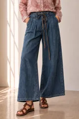 Jean azul de corte wide leg, tiro alto y diseño holgado, con cintura fruncida con elástico y cordón ajustable tipo lazo.