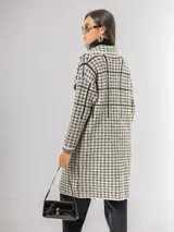 Sacón tipo tapado de corte recto y largo midi, con diseño de estampa pied de poule y solapas clásicas. Confeccionado en tejido abrigado y liviano, ideal para media estación.
