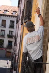 Remera color crema de corte holgado con mangas cortas y estampado en la espalda con el logo de la marca Ittai en color marrón.