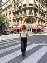 Corset de encaje color crema con escote estilo bardot y volados en los hombros. Presenta cierre frontal y diseño entallado.