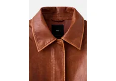 Chaqueta estilo aviador de cuero sintético marrón, con cuello de corderito sintético blanco, bolsillos frontales con solapa, cierre de cremallera y puños y cintura de canalé elástico.