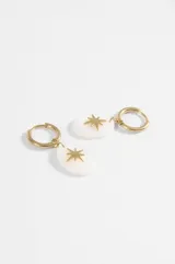 Aros de acero quirúrgico plateados con argolla y dije colgante ovalado de nácar blanco con detalle de estrella metálica en el centro.