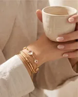Pulsera de acero con baño dorado, compuesta por una cadena fina con dijes circulares engastados de circonias transparentes facetadas.