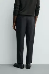 Pantalón de corte regular fit, color negro, confeccionado en tejido elástico. Presenta cintura elástica, cierre frontal con cremallera y botón, bolsillos laterales y bolsillos traseros de vivo.