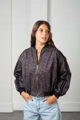 Campera tipo bomber de gamuza con estampado animal print en tonos bordó y negro. Presenta cierre frontal dorado, puños y cintura elástica en color negro, y detalle de franjas laterales en las mangas.