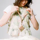 Llavero de cuello beige con estampado de lunares marrones, detalle de cuero sintético y gancho metálico.