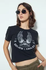 Remera cropped blanca de manga corta con escote a la base y estampa frontal de inspiración vintage con un águila, estrellas y el texto "Golden Eagles".