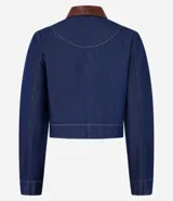 Campera de jean azul con cuello inglés de poliuretano color marrón. Cierre frontal con botones metálicos. Bolsillos de parche en el pecho con detalle de ribete de poliuretano marrón.