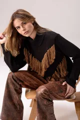 Sweater negro tejido de punto con cuello alto y silueta relajada, decorado con flecos marrones dispuestos en forma de V en la parte frontal.