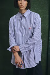 Camisa de corte oversize con estampado a rayas verticales en tonos azul y blanco, cuello clásico y cierre frontal con botones.