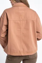 Sobrecamisa de algodón color marrón claro, con cuello camisero y cierre frontal de botones a presión. Presenta detalles de bordado vertical en el frente y en los puños.