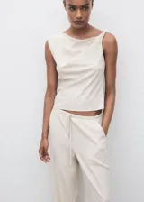 Pantalón largo color blanco crudo, de corte recto y tiro medio, con cintura elástica y cordón ajustable. Cuenta con dos bolsillos laterales.