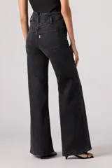 Pantalón de jean acampanado negro de tiro alto con dos botones a la vista.