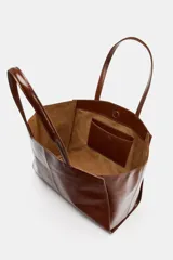 Bolso tipo shopper confeccionado en piel, con diseño de doble asa de hombro y cierre mediante botón imantado. Incluye bolsillo interior.