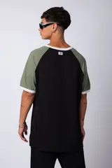 Remera estilo raglán color blanco en el cuerpo, con mangas en tono tostado y ribetes en color verde militar en el cuello y los puños.