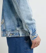 Campera de jean azul claro con efecto delavé, roturas, desgastes y bolsillos frontales con solapa.