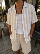 Camisa de manga corta a rayas verticales en tonos blanco y arena, con cuello cubano y cierre frontal de botones.