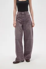 Pantalon de jean estilo barrel con tiro alto, diseño de paneles reforzados en las piernas y costuras visibles con remaches metálicos.